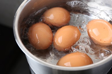 Photo of Chicken eggs boiling in saucepan, closeup view