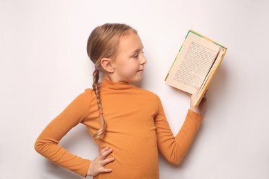 Happy little girl reading book on white background