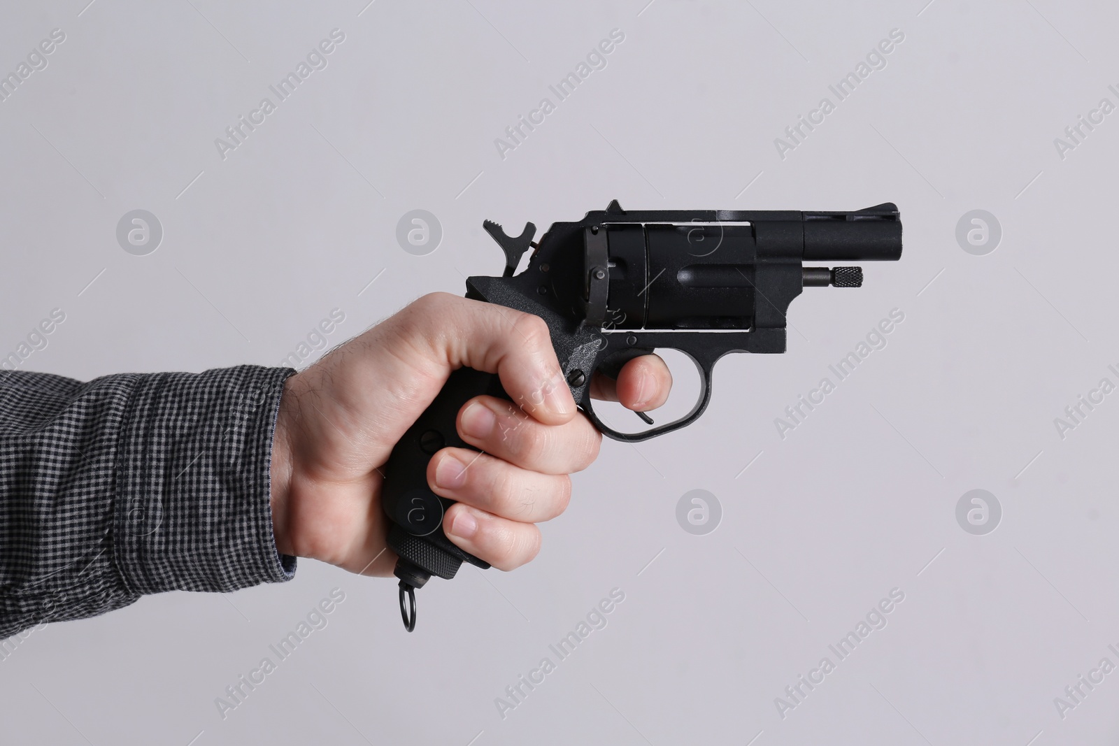 Photo of Man holding gun on grey background, closeup