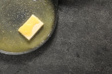 Photo of Melting butter in frying pan on grey table, top view. Space for text