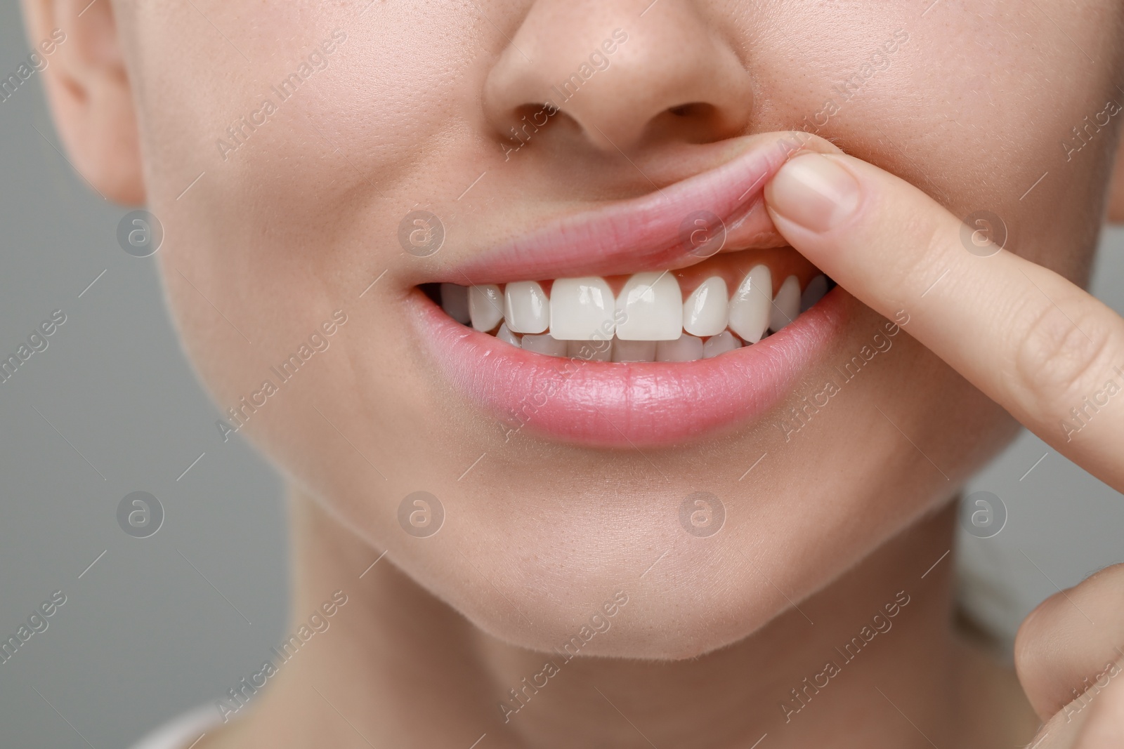 Photo of Woman showing healthy gums on grey background, closeup