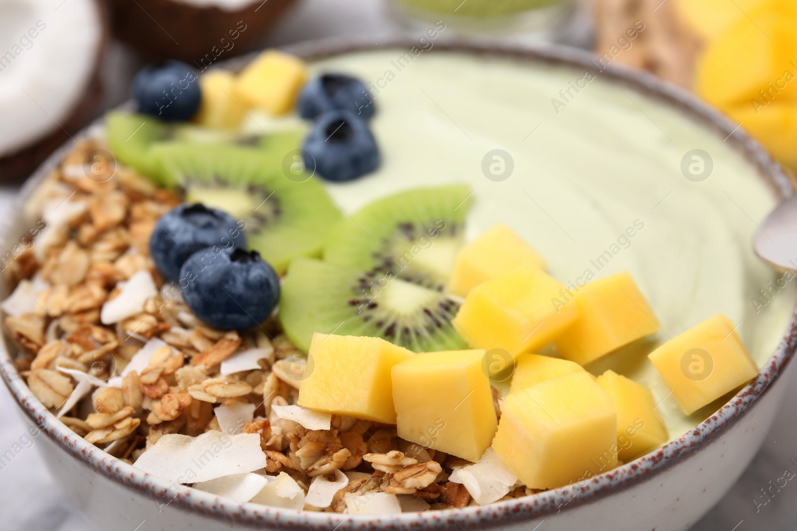 Photo of Tasty matcha smoothie bowl served with fresh fruits and oatmeal on table, closeup. Healthy breakfast
