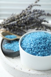Photo of Bowl with blue sea salt and lavender flowers on white table, closeup. Space for text