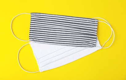 Photo of Homemade protective face masks on yellow background, flat lay