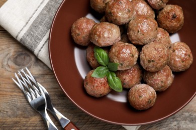 Photo of Tasty cooked meatballs with basil served on wooden table, flat lay