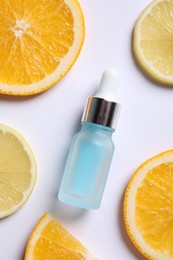 Photo of Bottle of cosmetic serum and sliced citrus fruits on white background, flat lay