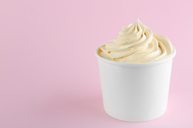 Photo of Cup with tasty frozen yogurt on pink background. Space for text