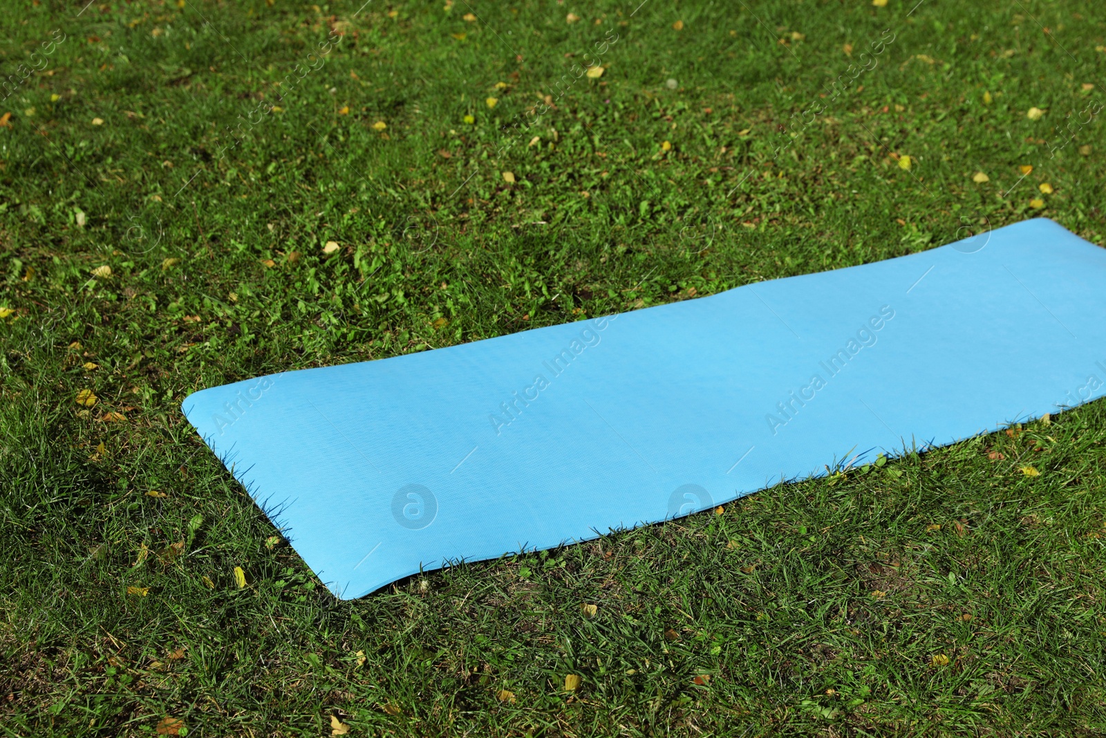 Photo of Blue karemat or fitness mat on fresh green grass outdoors