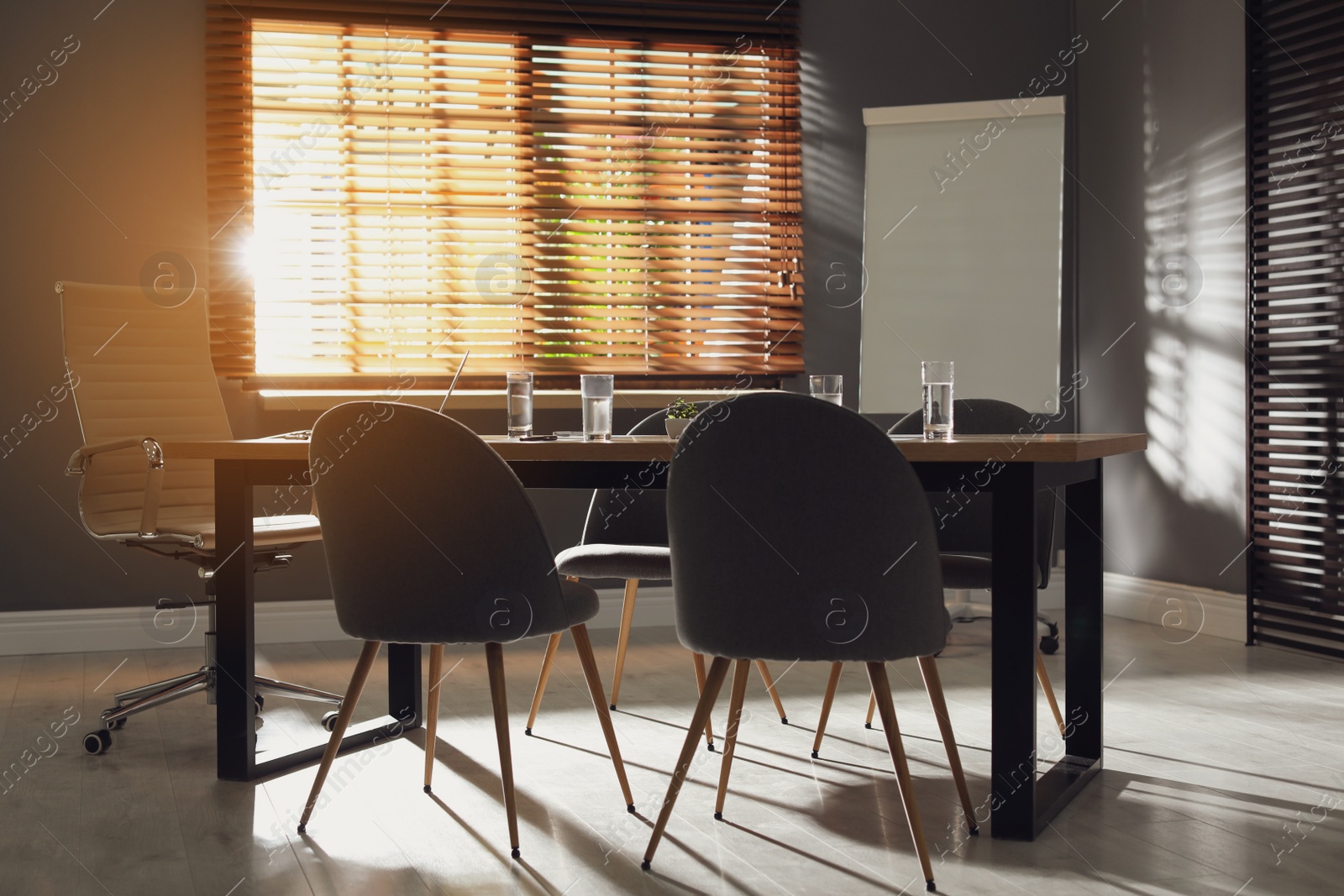 Photo of Stylish office interior with wooden table and flipchart