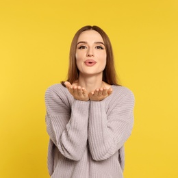 Beautiful young woman in sweater on yellow background. Winter season