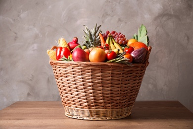 Assortment of fresh organic fruits and vegetables in basket on wooden table