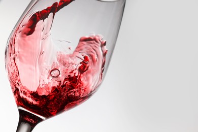 Photo of Pouring tasty red wine in glass on white background, closeup. Space for text