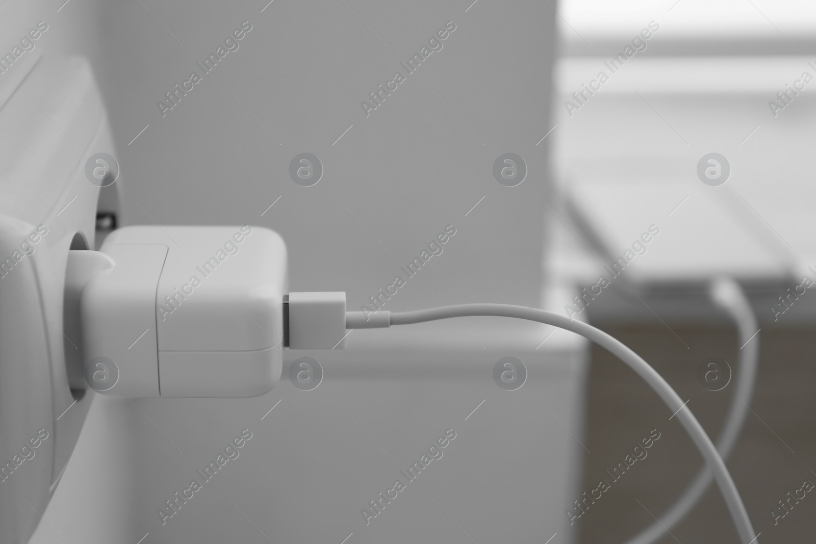 Photo of Modern smartphone charging from electric socket, closeup