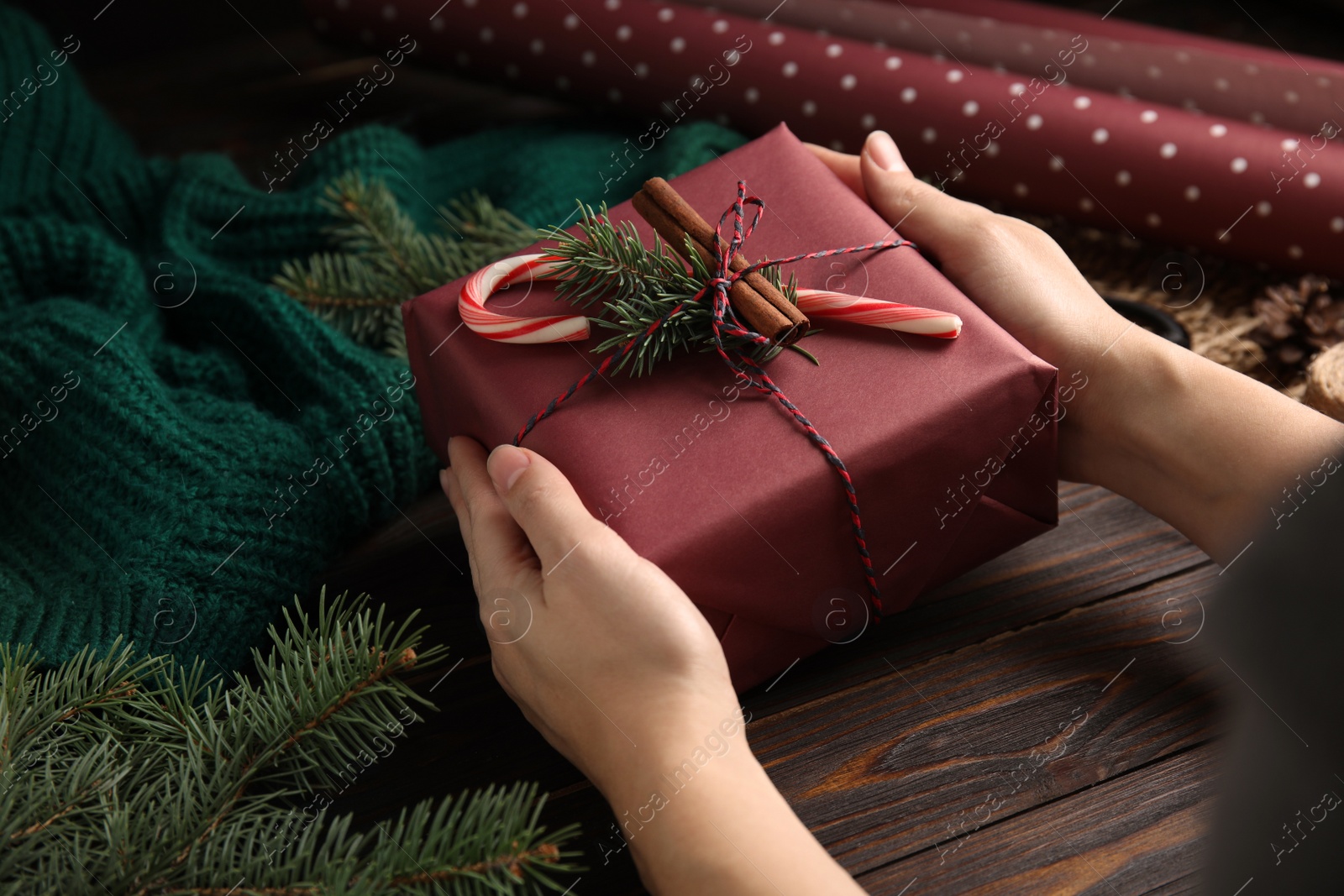 Photo of Woman with gift box at wooden table, closeup