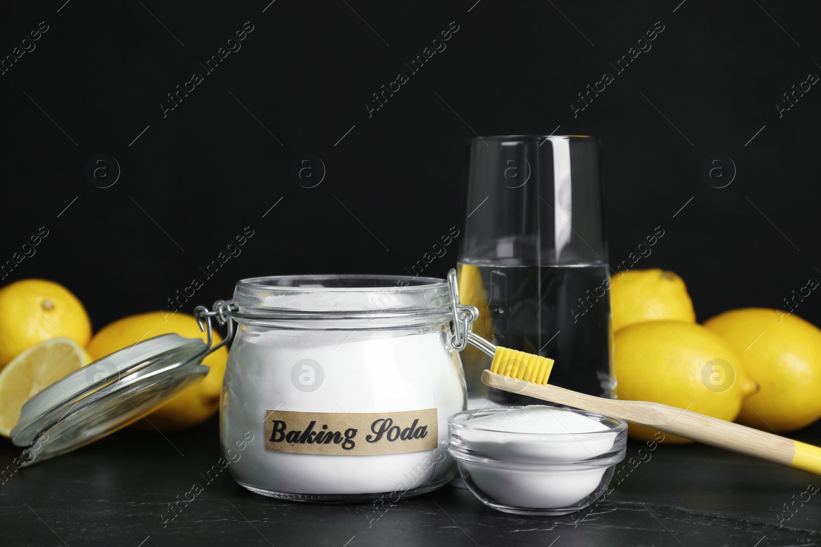 Photo of Composition with baking soda and bamboo toothbrush on black table