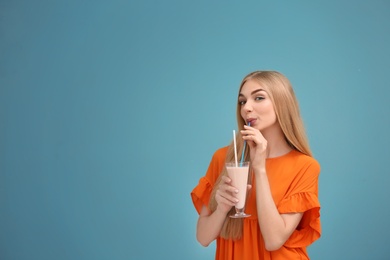 Photo of Young woman with glass of delicious milk shake on color background