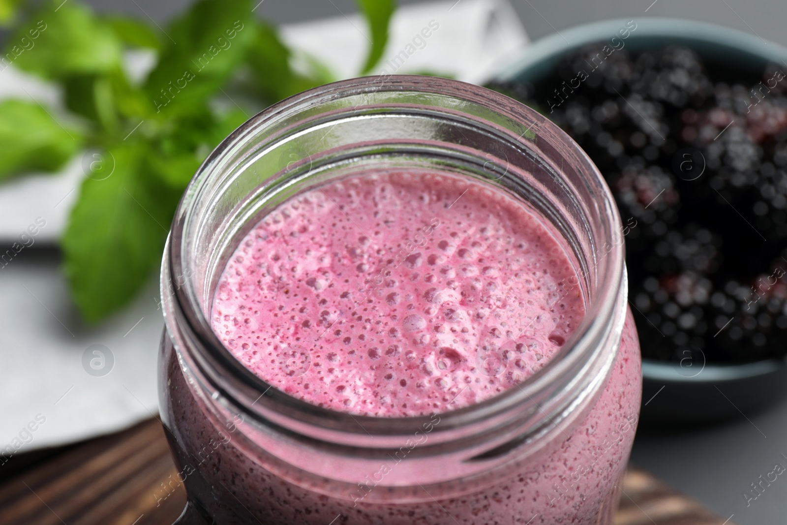 Photo of Mason jar of blackberry smoothie on table, closeup