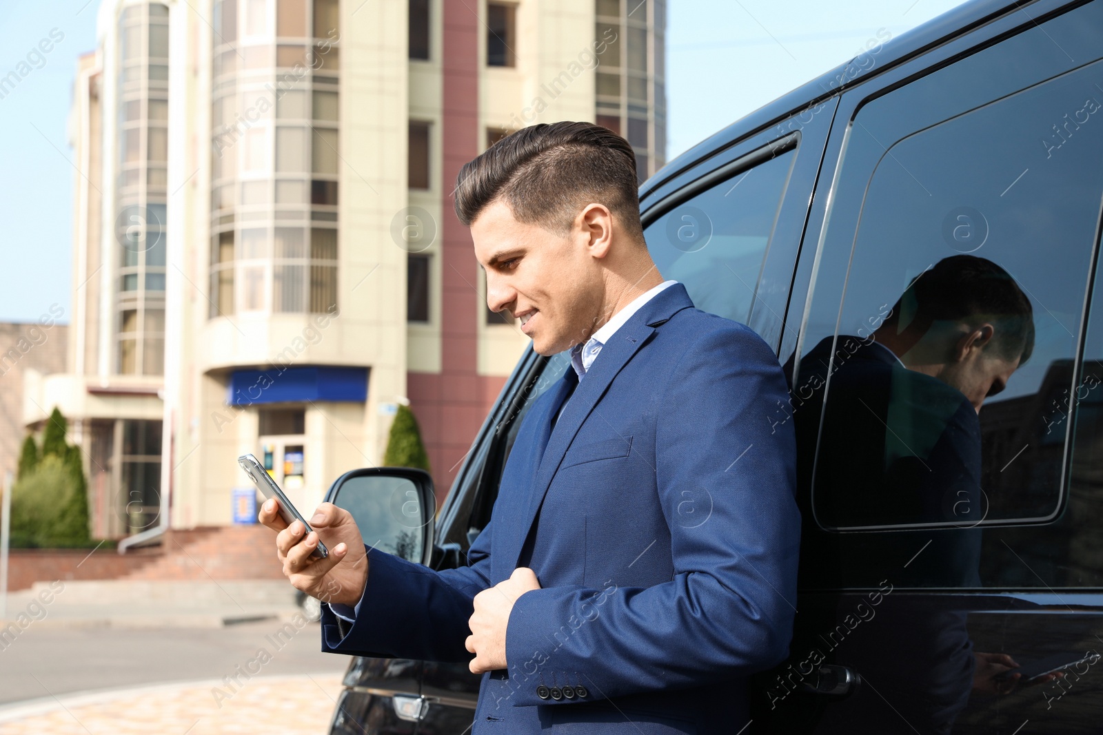 Photo of Handsome man with smartphone near modern car outdoors