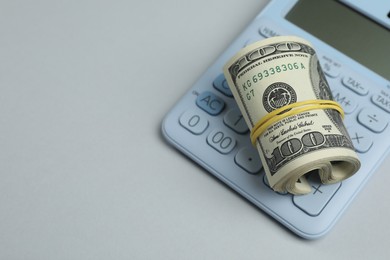Photo of Money exchange. Dollar banknotes and calculator on gray background, closeup. Space for text