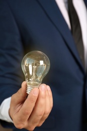 Photo of Businessman in suit holding lamp bulb, closeup