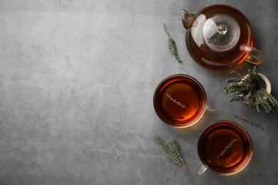 Aromatic herbal tea with thyme on grey table, flat lay. Space for text