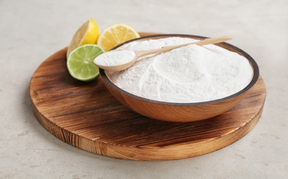 Bowl with baking soda and lemons on wooden board