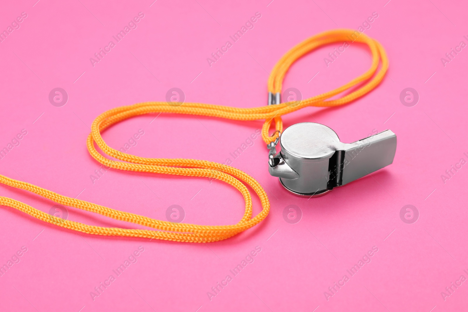 Photo of One metal whistle with cord on pink background