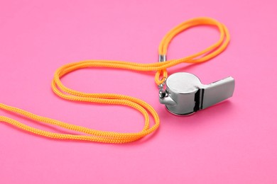 Photo of One metal whistle with cord on pink background