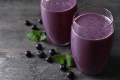 Tasty acai drink in glasses and berries on grey table, closeup. Space for text