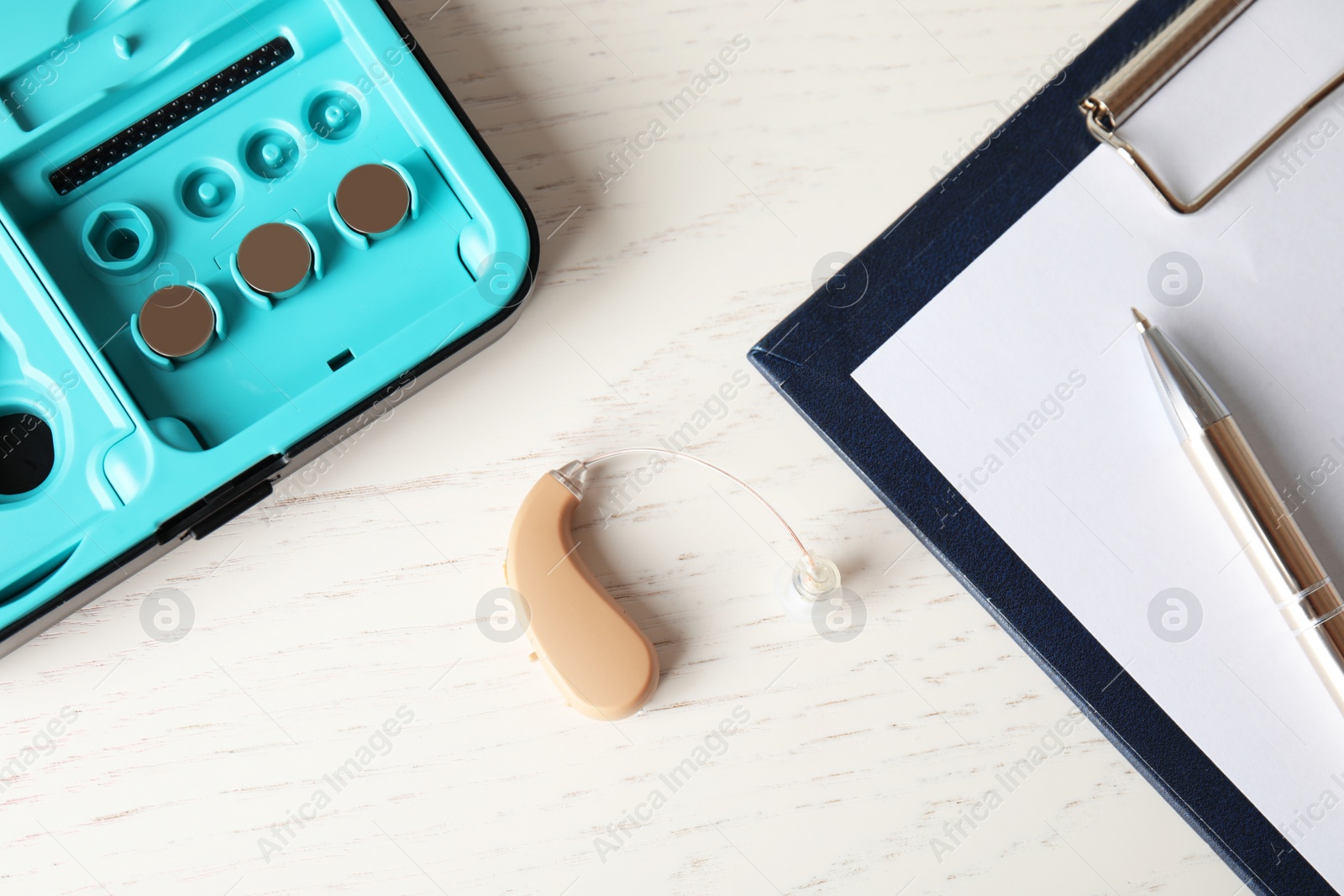 Photo of Hearing aid and case on white wooden table, top view