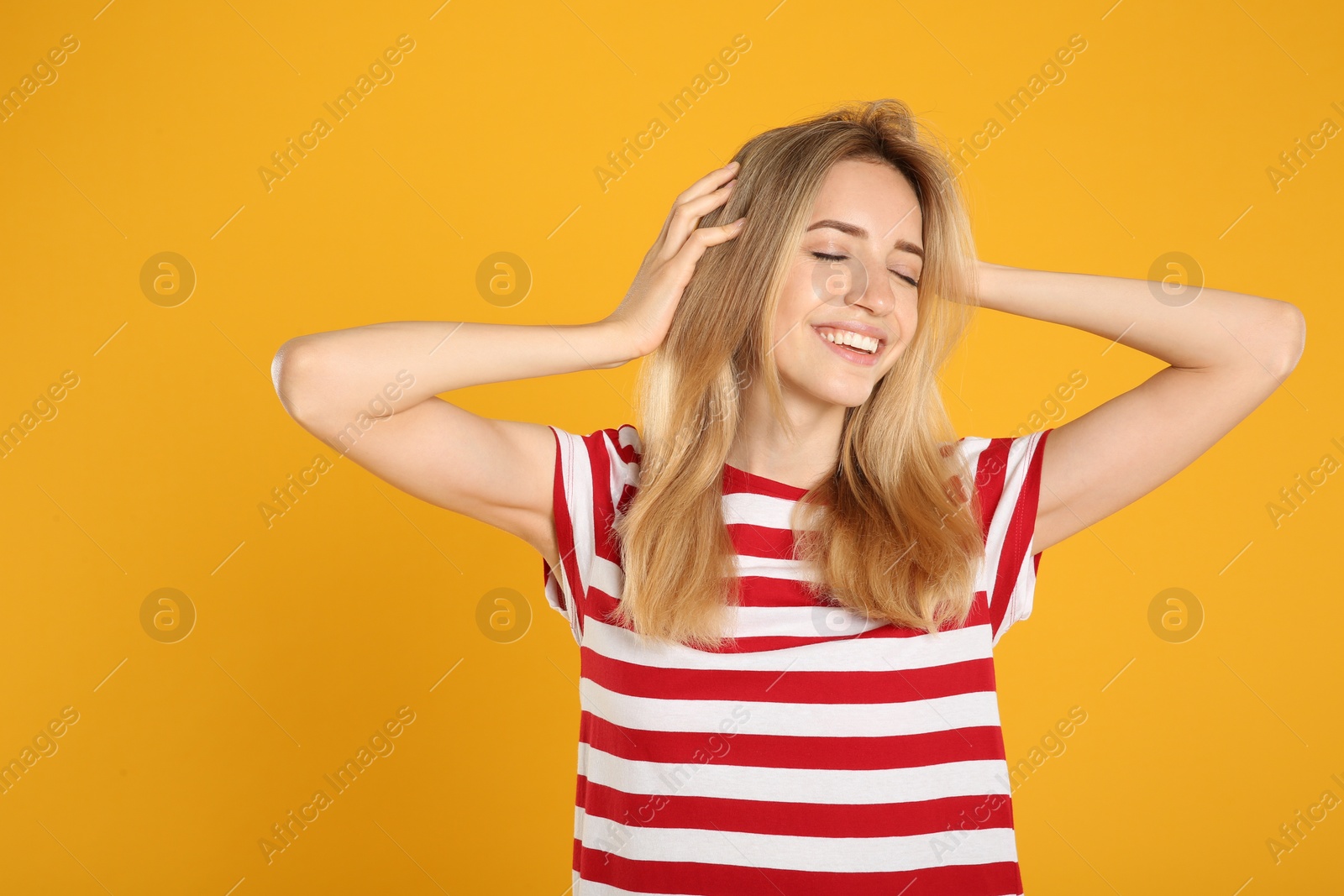 Photo of Portrait of beautiful young woman with blonde hair on yellow background