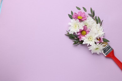 Photo of Brush with colorful flowers of chrysanthemum on violet background, top view. Space for text. Creative concept
