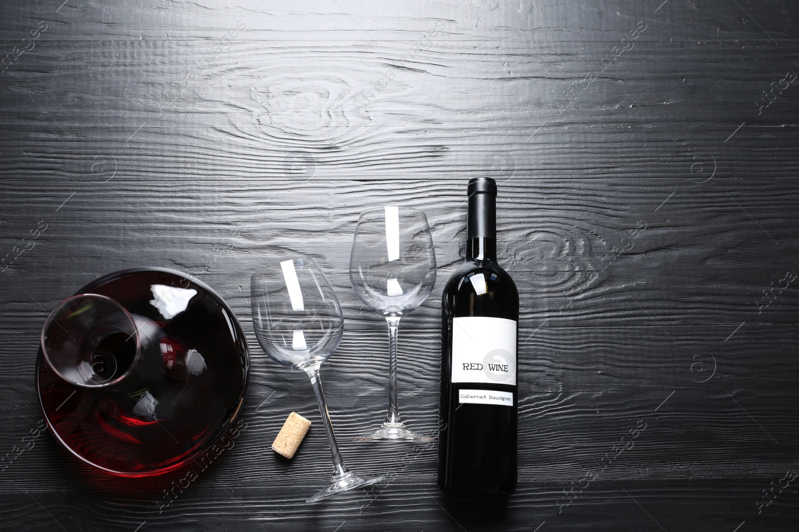 Photo of Decanter, glasses and bottle with red wine on wooden background, flat lay. Space for text