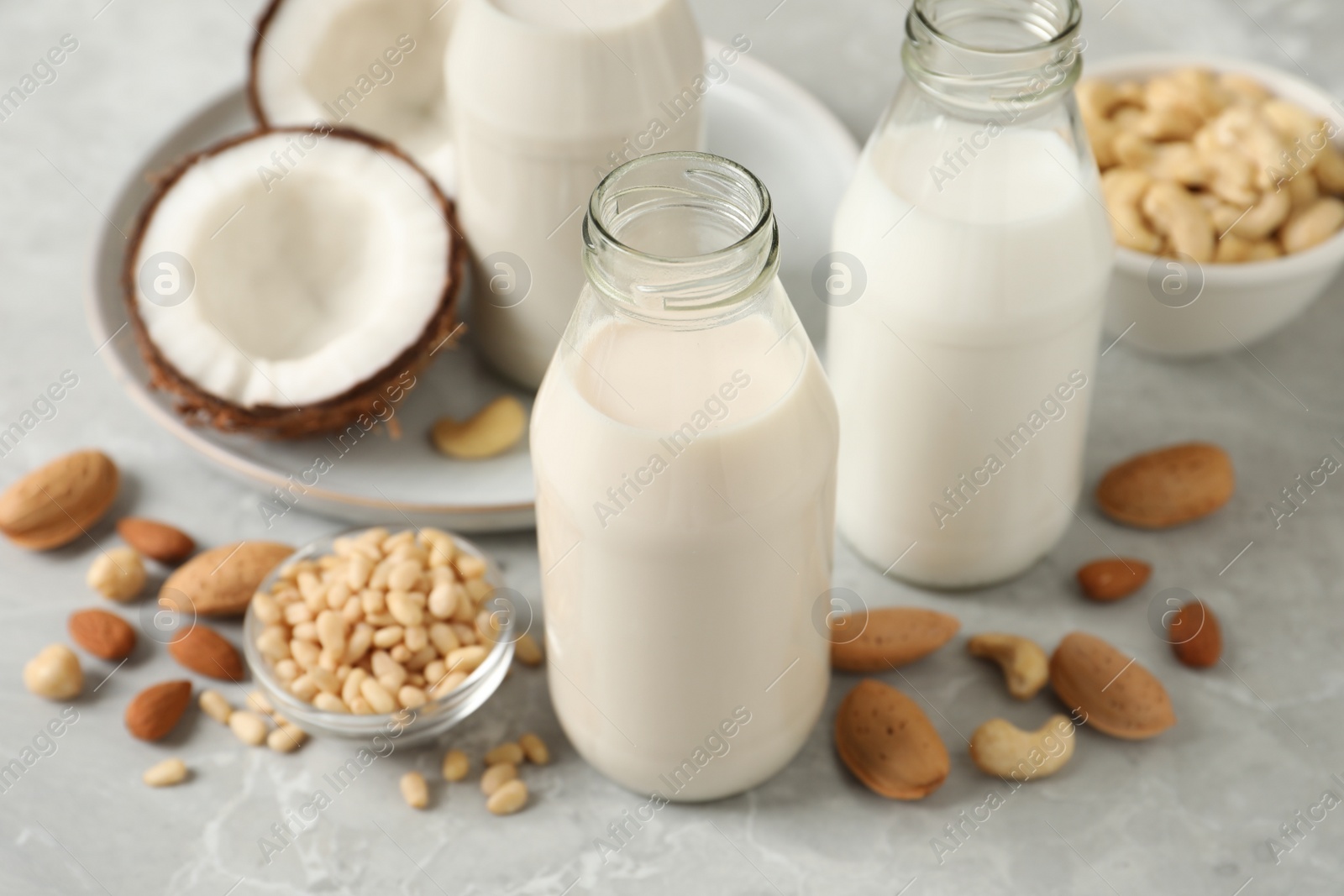 Photo of Different nut milks on light grey marble table