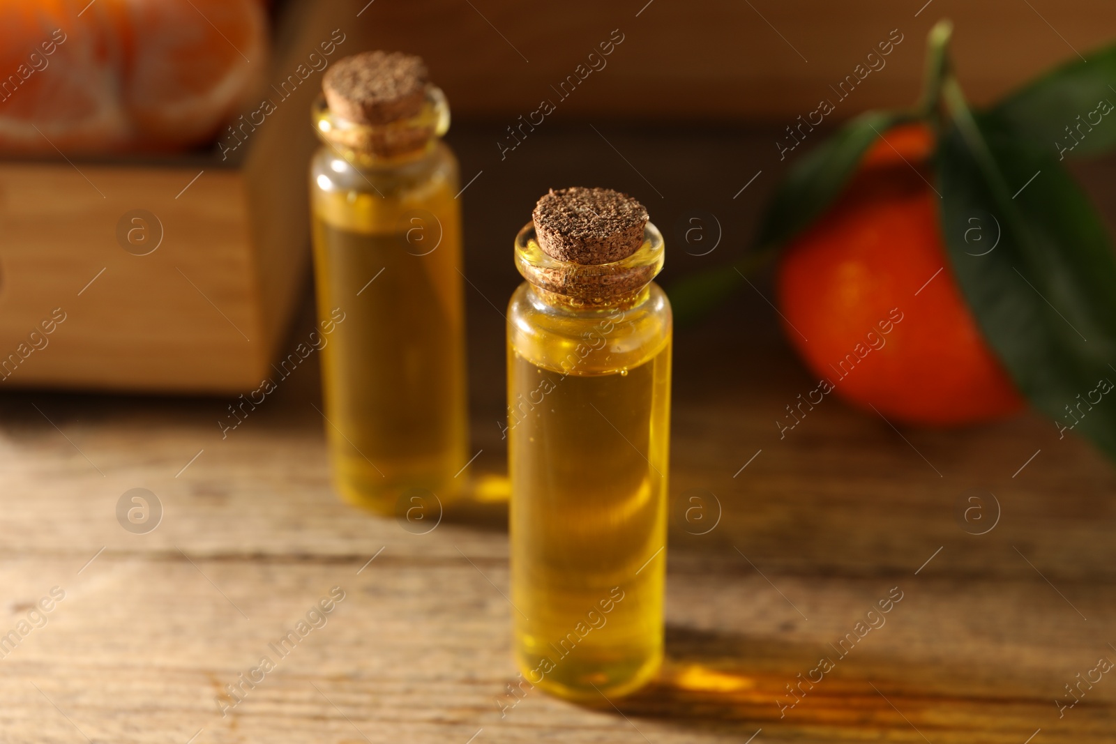 Photo of Bottles of tangerine essential oil on wooden table, closeup