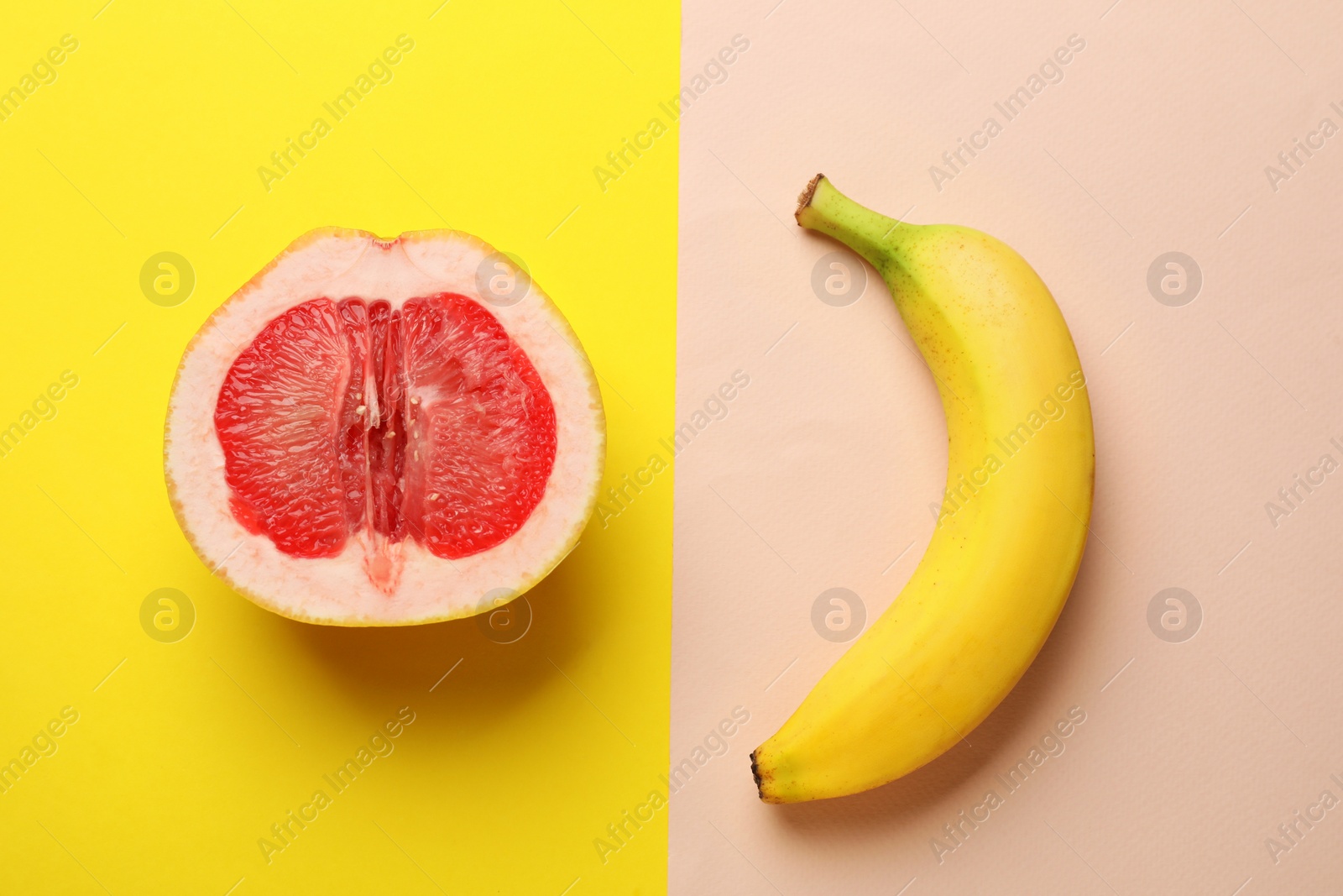 Photo of Banana and half of grapefruit on color background, flat lay. Sex concept