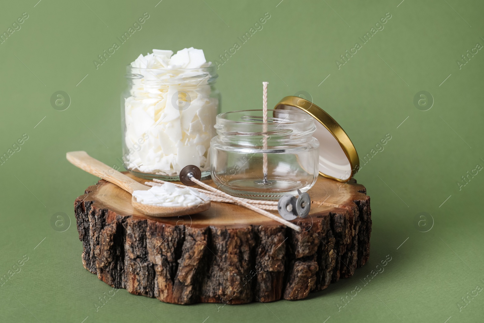 Photo of Ingredients for homemade candle on wooden stump against green background