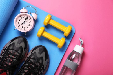 Photo of Sneakers, dumbbells, fitness mat and bottle of water on pink background, flat lay with space for text. Morning exercise