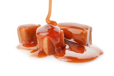 Pouring caramel sauce onto delicious candies on white background