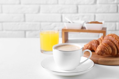 Photo of Breakfast time. Fresh croissants and coffee on white table. Space for text