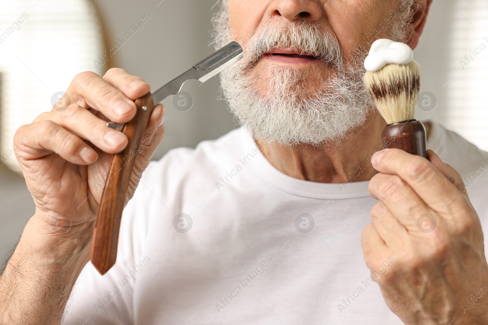 Photo of Man shaving mustache with blade in bathroom, closeup