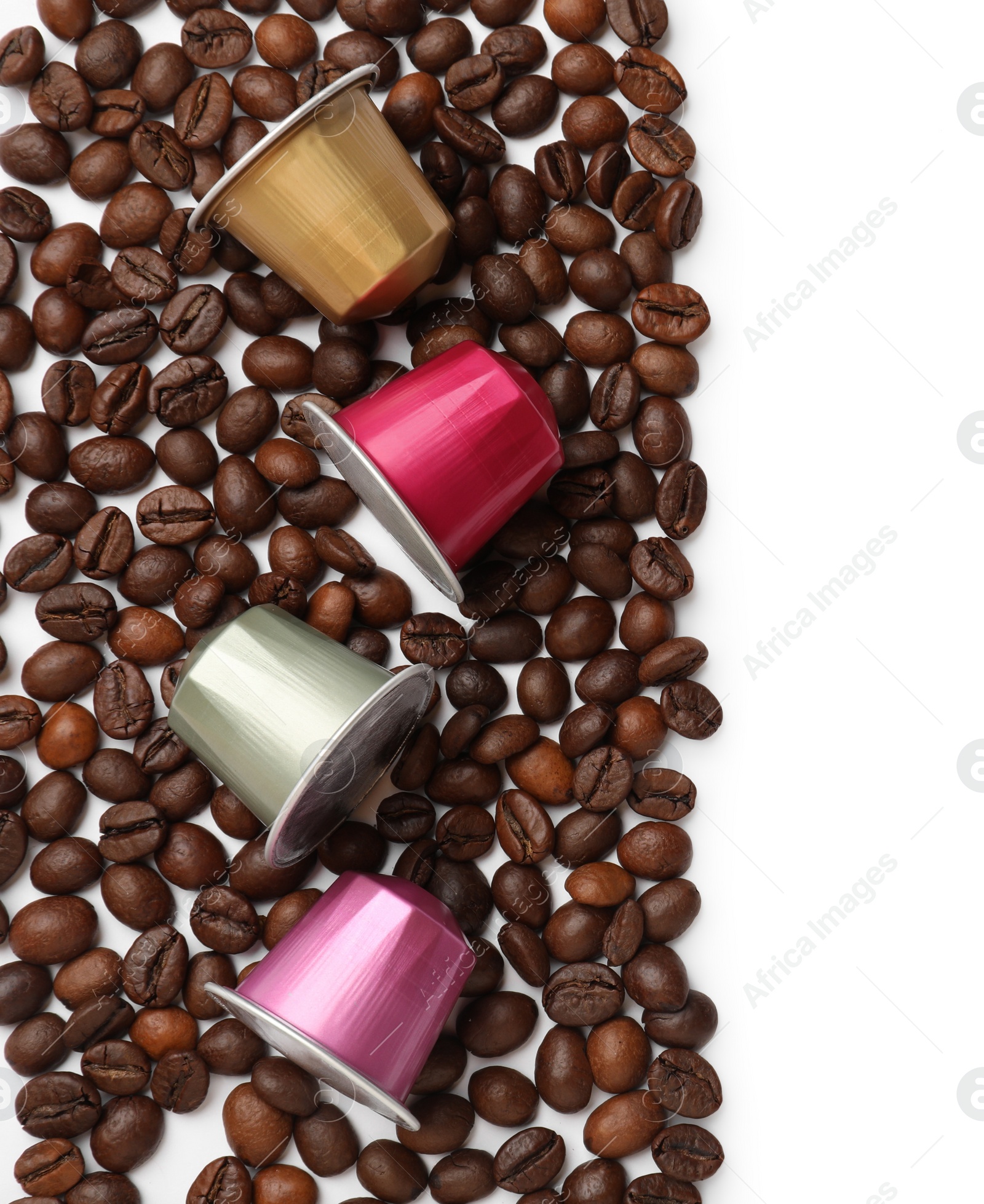 Photo of Many coffee capsules and beans on white background, top view. Space for text