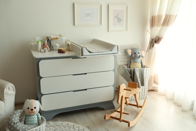 Photo of Beautiful baby room interior with toys and modern changing table