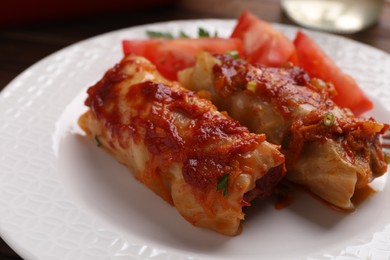 Photo of Delicious stuffed cabbage rolls cooked with homemade tomato sauce on plate, closeup