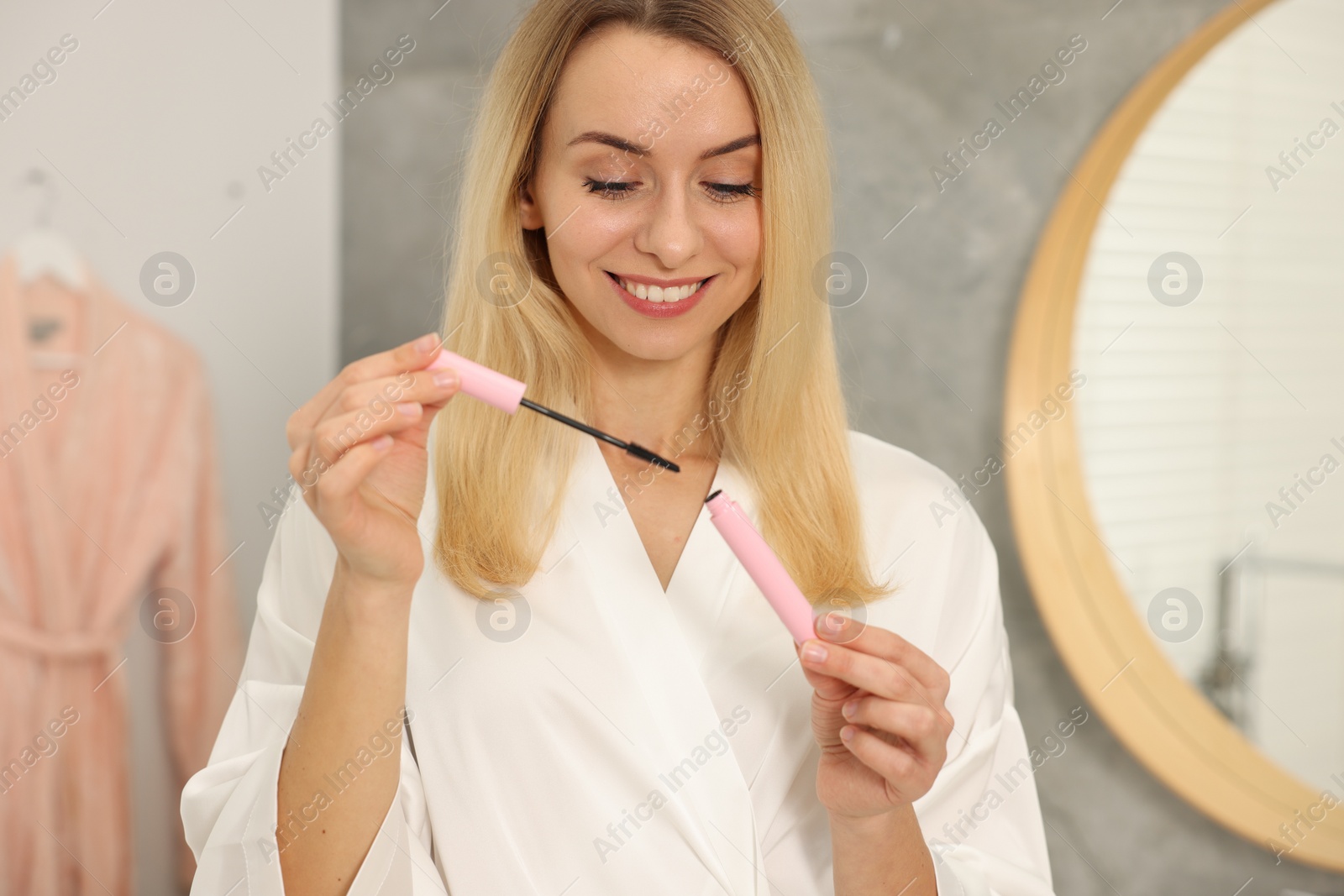 Photo of Beautiful happy woman with mascara in bathroom