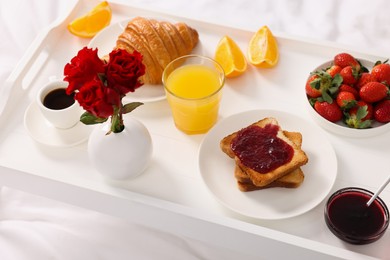 Photo of Tray with delicious breakfast on bed, closeup