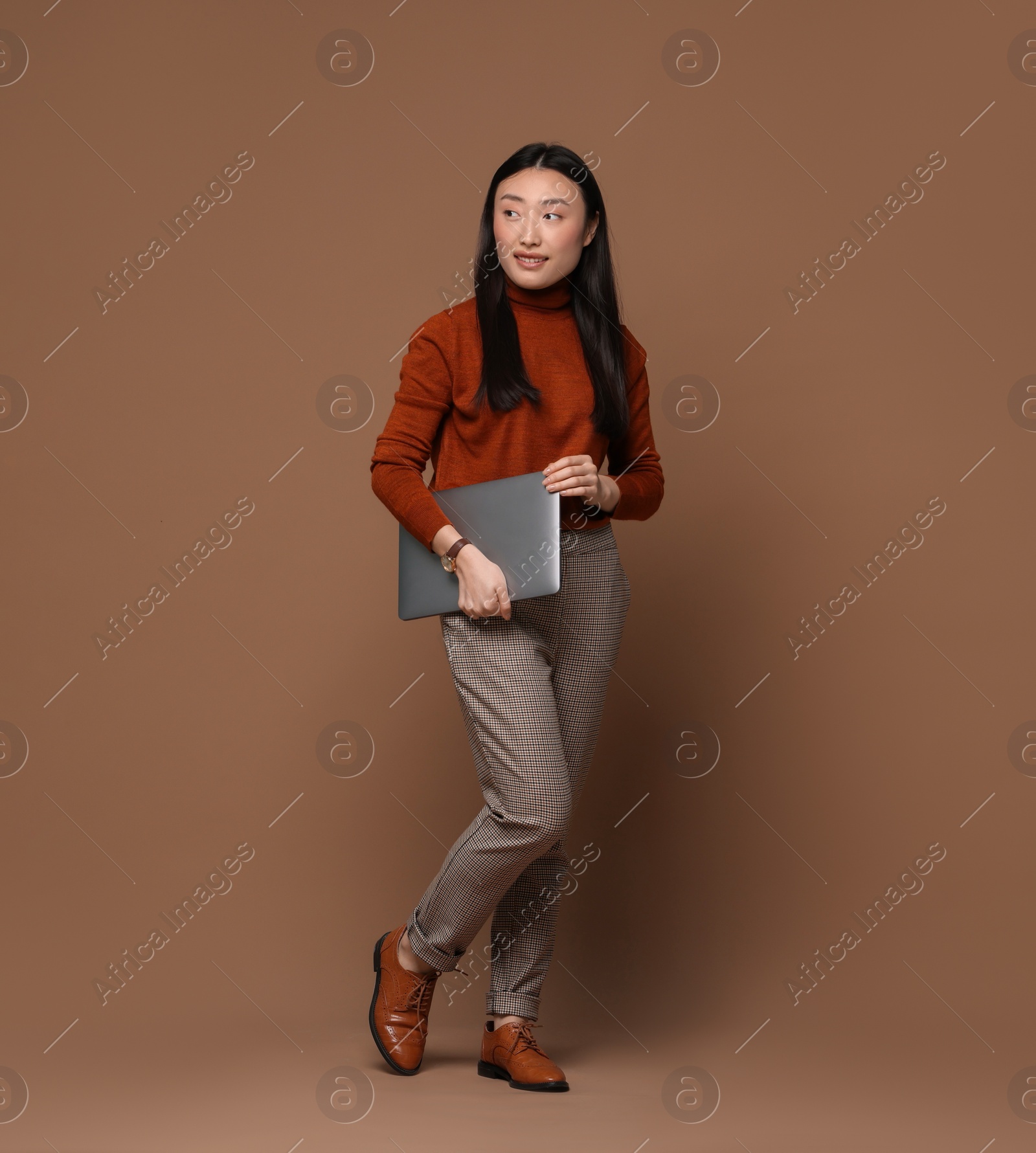 Photo of Full length portrait of smiling woman with laptop on brown background. Space for text