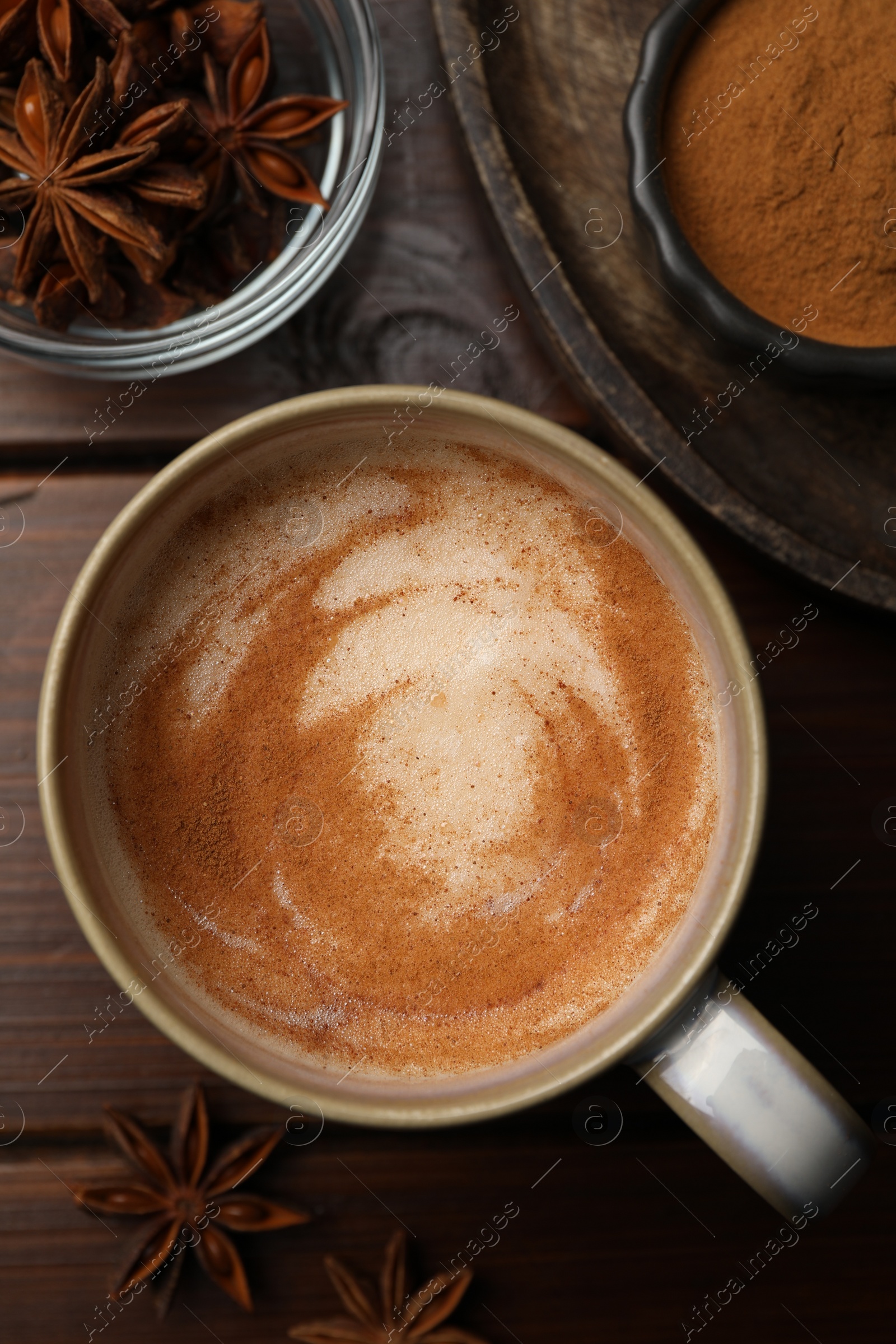 Photo of Cup of delicious eggnog with anise on wooden table, flat lay