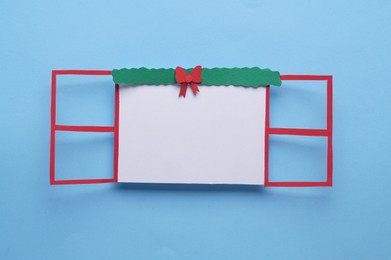 Photo of Open paper window frame with Christmas decoration on light blue background. Space for text