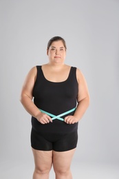 Overweight woman measuring waist before weight loss on color background
